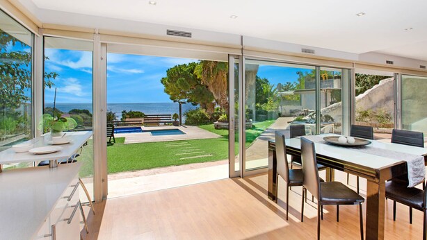 A modern dining area with a view of a pool and garden.