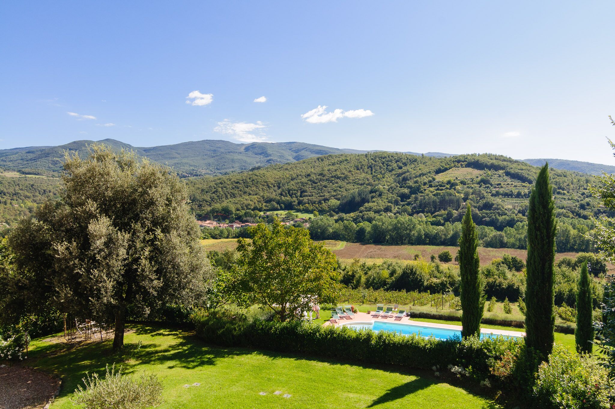 A pool area with a view of a lush green landscape and hills in the background.