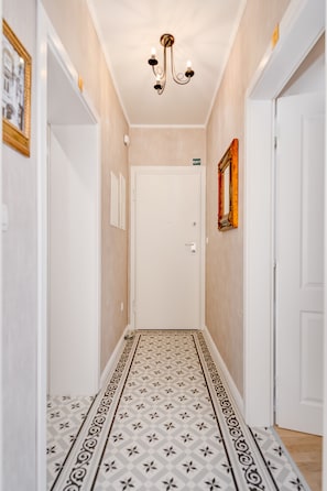 A hallway with patterned flooring, a white door, and a chandelier. - Le Monde Luxury Accommodation (Split)