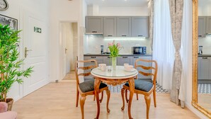A modern kitchen with grey cabinets, a round glass table with chairs, and a vase with flowers. - Le Monde Luxury Accommodation (Split)