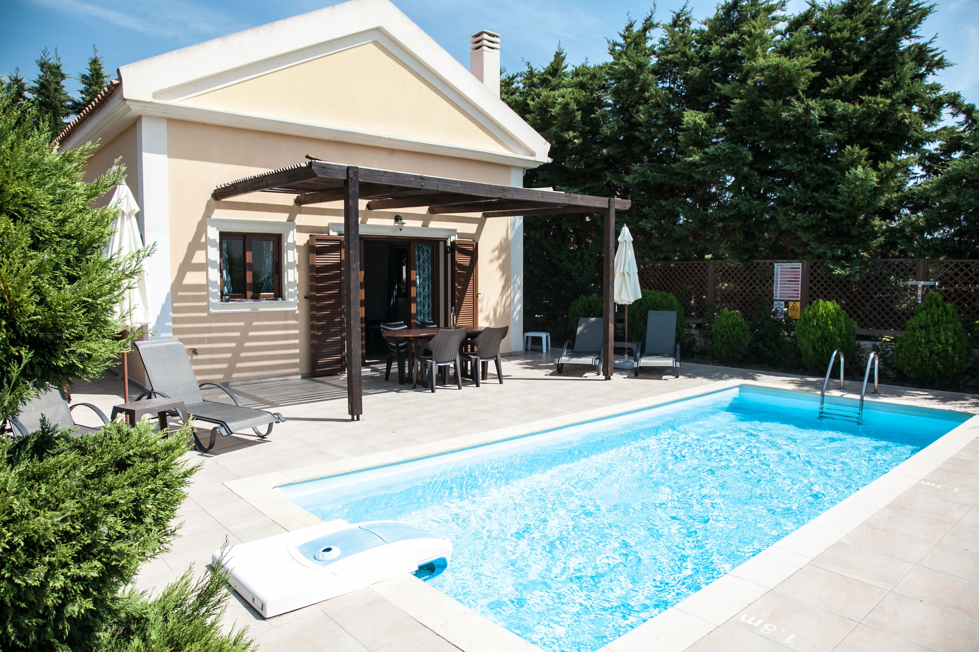 Una proprietà residenziale con piscina, area salotto all'aperto e portico coperto.