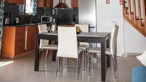 A spacious kitchen with wooden beams, a dining area with a table and chairs, and a staircase leading to an upper level. - Villa Anthia (Kefalonia)