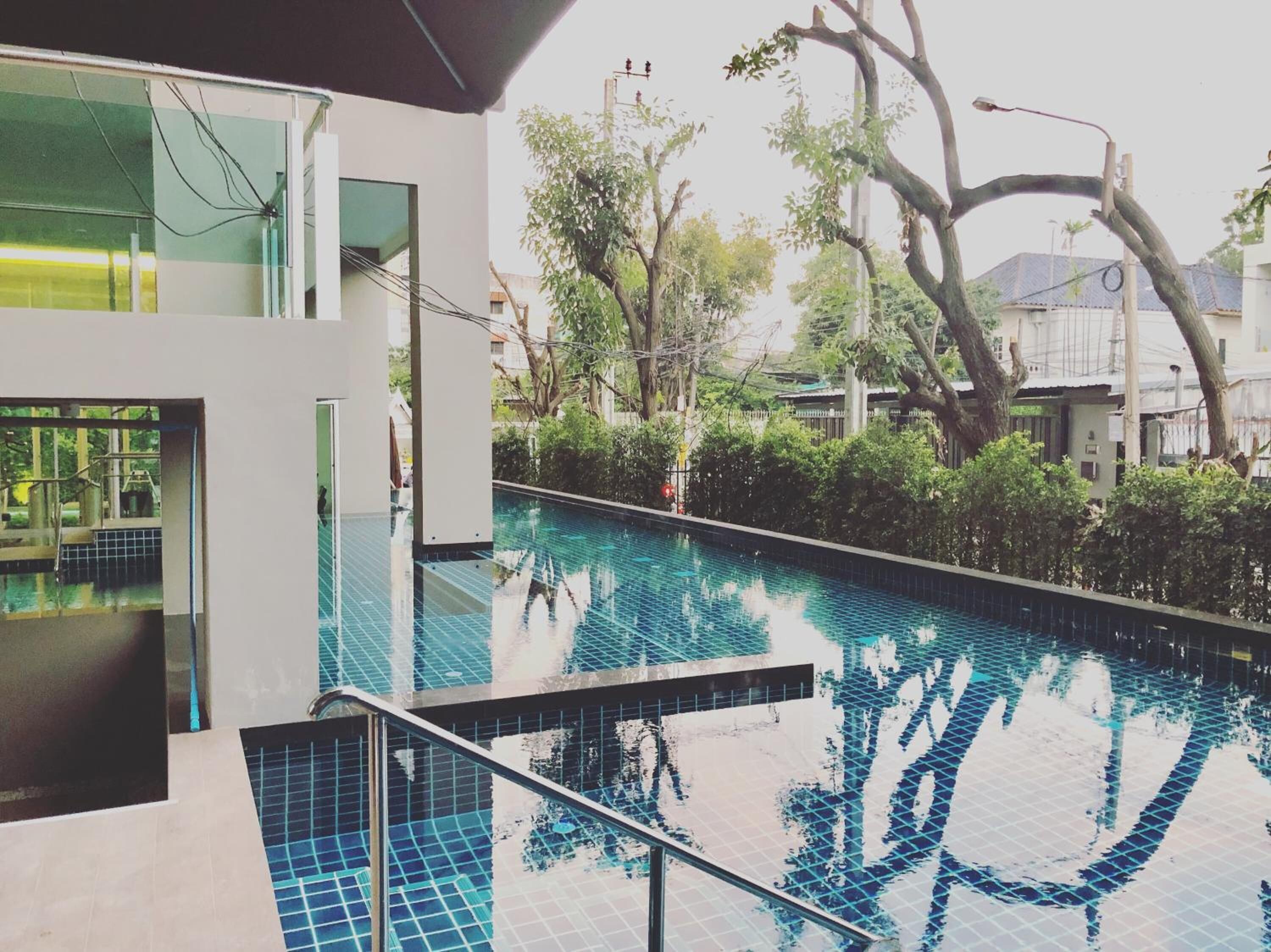 Un edificio moderno con piscina, rodeado de árboles y vegetación.