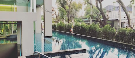 Un edificio moderno con piscina, rodeado de árboles y vegetación.