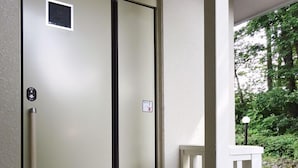 A double door with a handle and a small square window, a white railing, and a concrete floor. - Family Lodge Hatagoya Nikko Kinugawa (Nikko)
