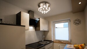 A modern kitchen with a built-in stove, a sink, and a window with blinds. - Blissberg Winterberg (Winterberg)