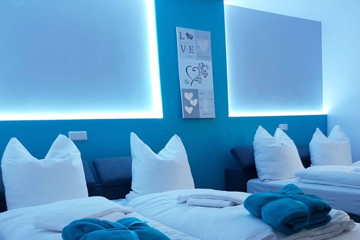 A hotel room with two beds, white bedding, and a blue accent wall.