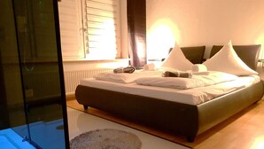 A modern bedroom with a large bed, a glass shower enclosure, and a round rug. - Blissberg Winterberg (Winterberg)