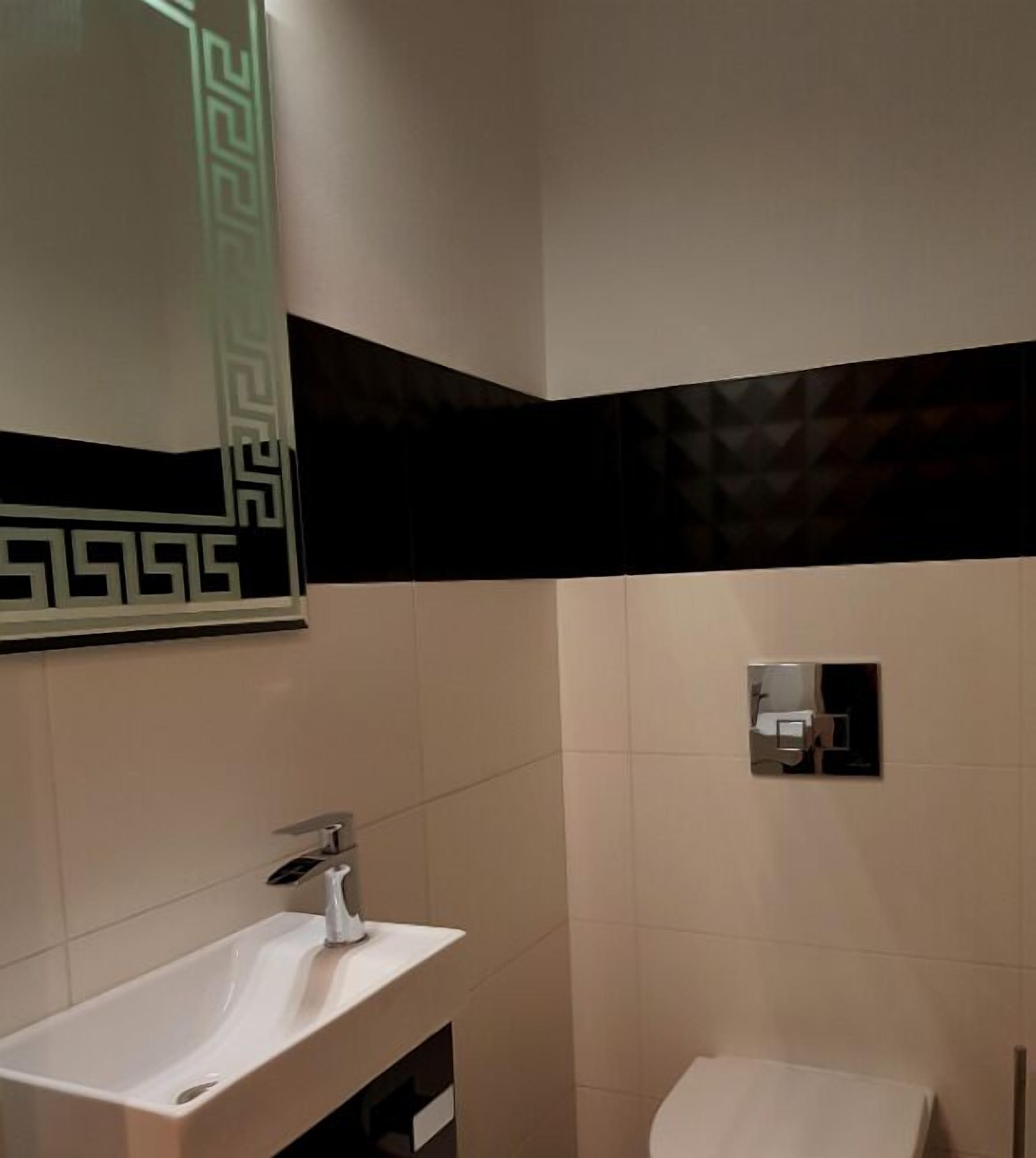A bathroom with a white sink, a mirror, and a toilet.