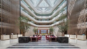 Eine geräumige Lobby mit hoher Decke, modernem Design und einer zentralen Sitzecke.