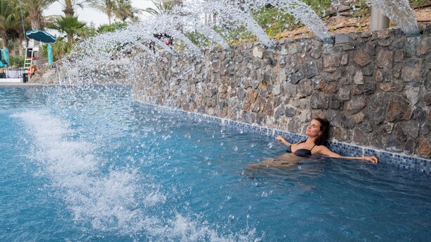Eine Frau entspannt sich in einem Pool mit Wasserspielen.