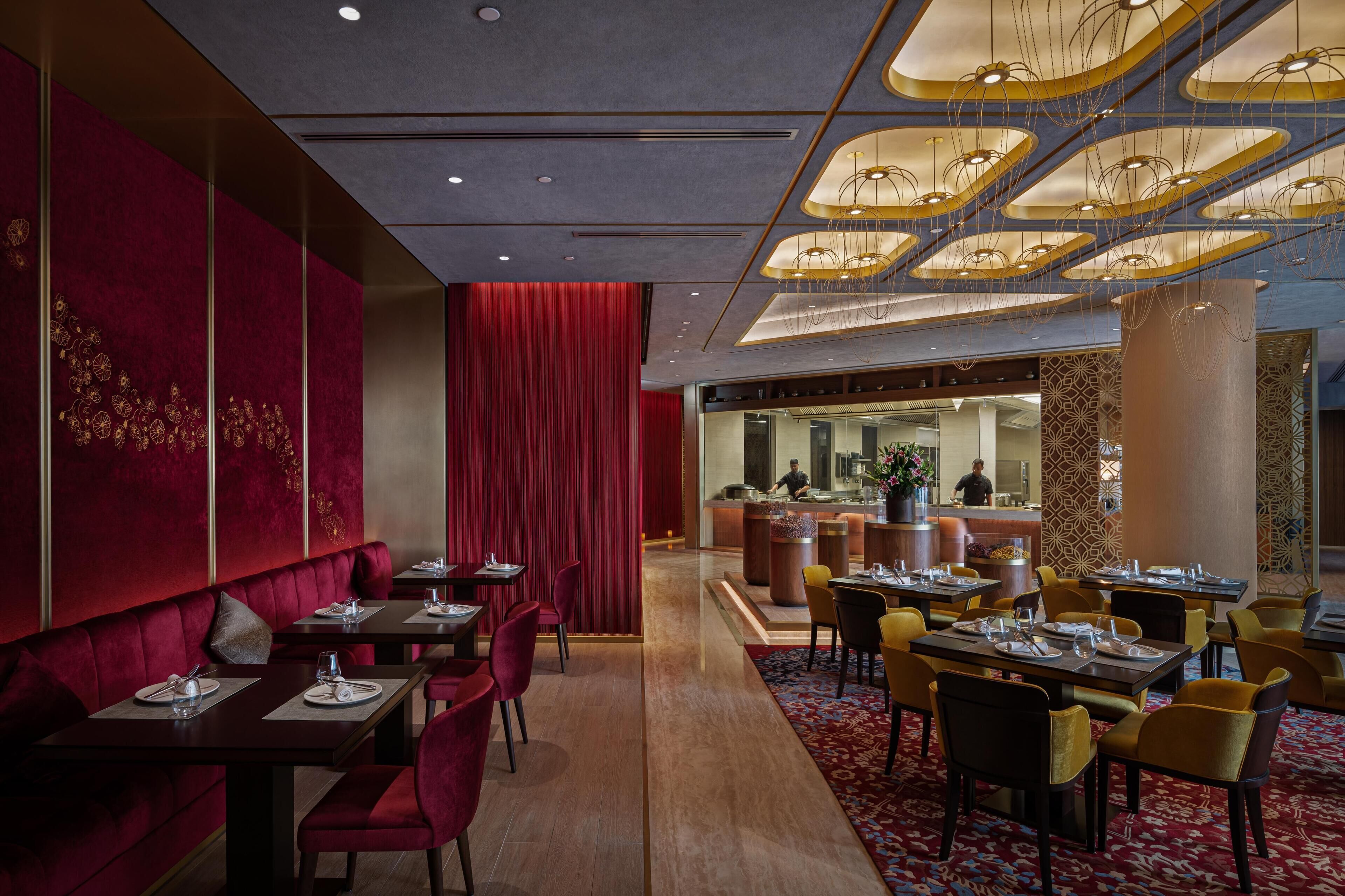 Un restaurant avec des banquettes en velours rouge, des chaises jaunes et un tapis à motifs.