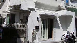 Un immeuble à plusieurs étages, doté d’une façade blanche, de nombreuses fenêtres et de câbles électriques apparents.