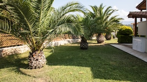 A well-maintained garden with palm trees and a stone wall. - Villa Artemis (Kefalonia)
