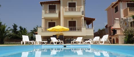 A pool area with lounge chairs and a yellow umbrella.