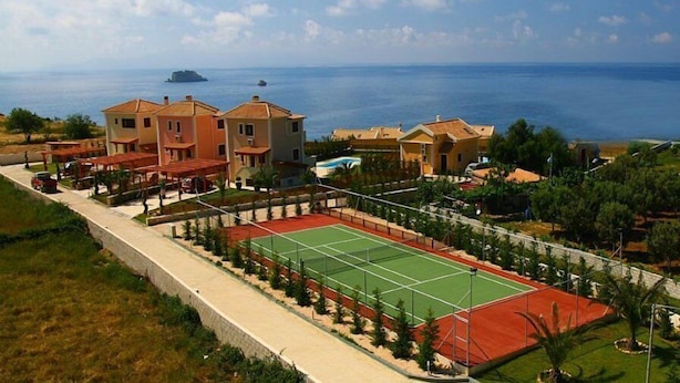 A coastal property with multiple buildings, a tennis court, and a view of the sea. - Villa Artemis (Kefalonia)