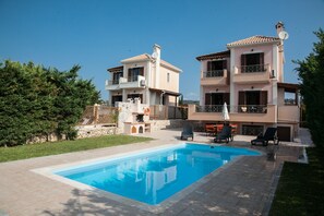 A two-story building with a swimming pool, outdoor seating, and a stone wall. - Villa Aethra (Kefalonia)