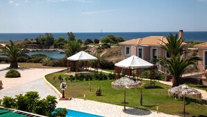 A resort with a pool, outdoor seating, and a view of the sea.