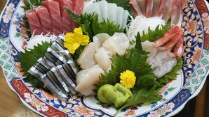 En tallerken med sashimi af forskellige fisketyper og tilbehør.