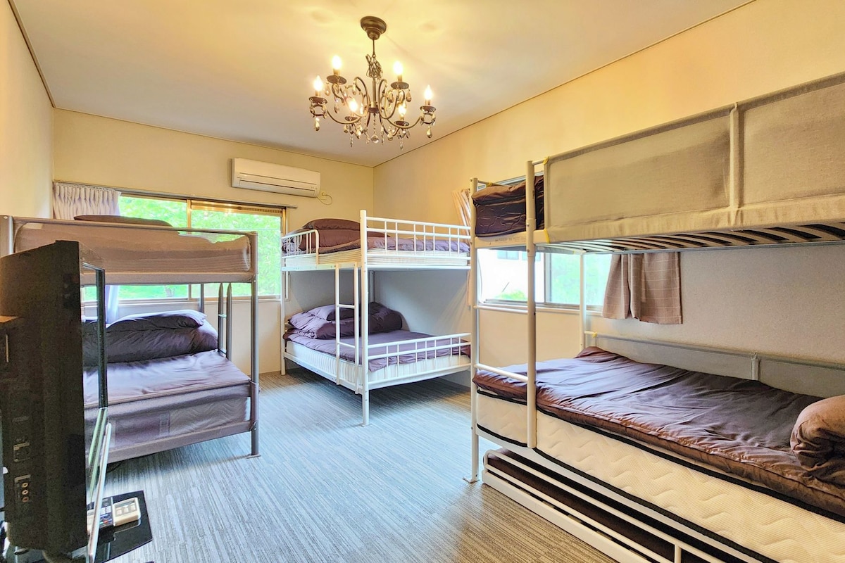 A bunk bed room with a chandelier, an air conditioning unit, and a window with curtains.