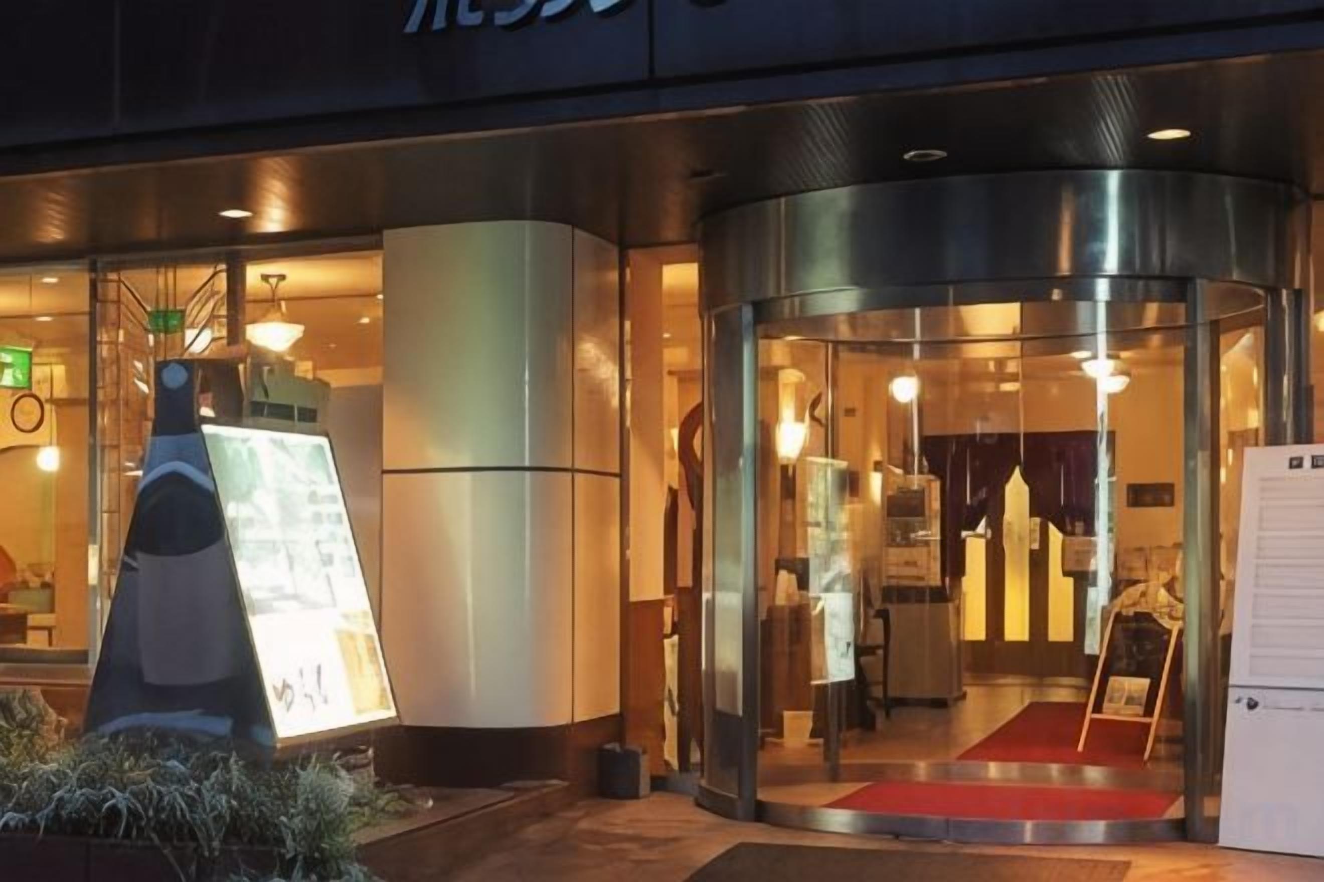 A hotel entrance with a revolving door, a reception desk, and a red carpet leading inside.