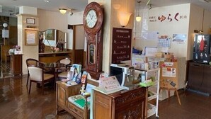 A traditional Japanese room with a wooden desk, chairs, a large clock, and a wall-mounted information board. - Niigata Hotel Terminal Inn (Niigata)