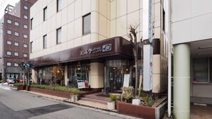 A modern building with a sign in Japanese, a glass entrance, and a small garden area with plants. - Niigata Hotel Terminal Inn (Niigata)