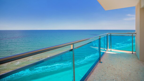 A balcony with a glass railing overlooking a turquoise sea and a clear sky. - Hotel Servigroup Koral Beach (Oropesa del Mar)
