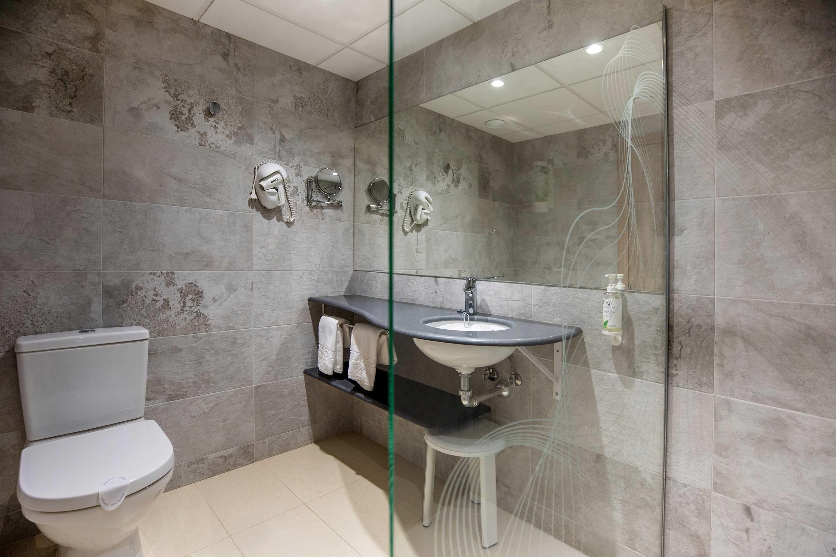 Une salle de bain moderne équipée de toilettes, d’un lavabo et d’une douche à parois de verre.