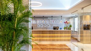 A reception area with a marble reception desk, a wooden counter, and a glass wall. - Hotel Servigroup Koral Beach (Oropesa del Mar)