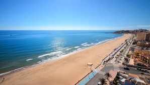 A coastal cityscape with a wide beach, a promenade, and buildings along the shore. - Hotel Servigroup Koral Beach (Oropesa del Mar)