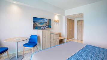 A hotel room with a bed, a desk with a chair, a small table, and a wardrobe.