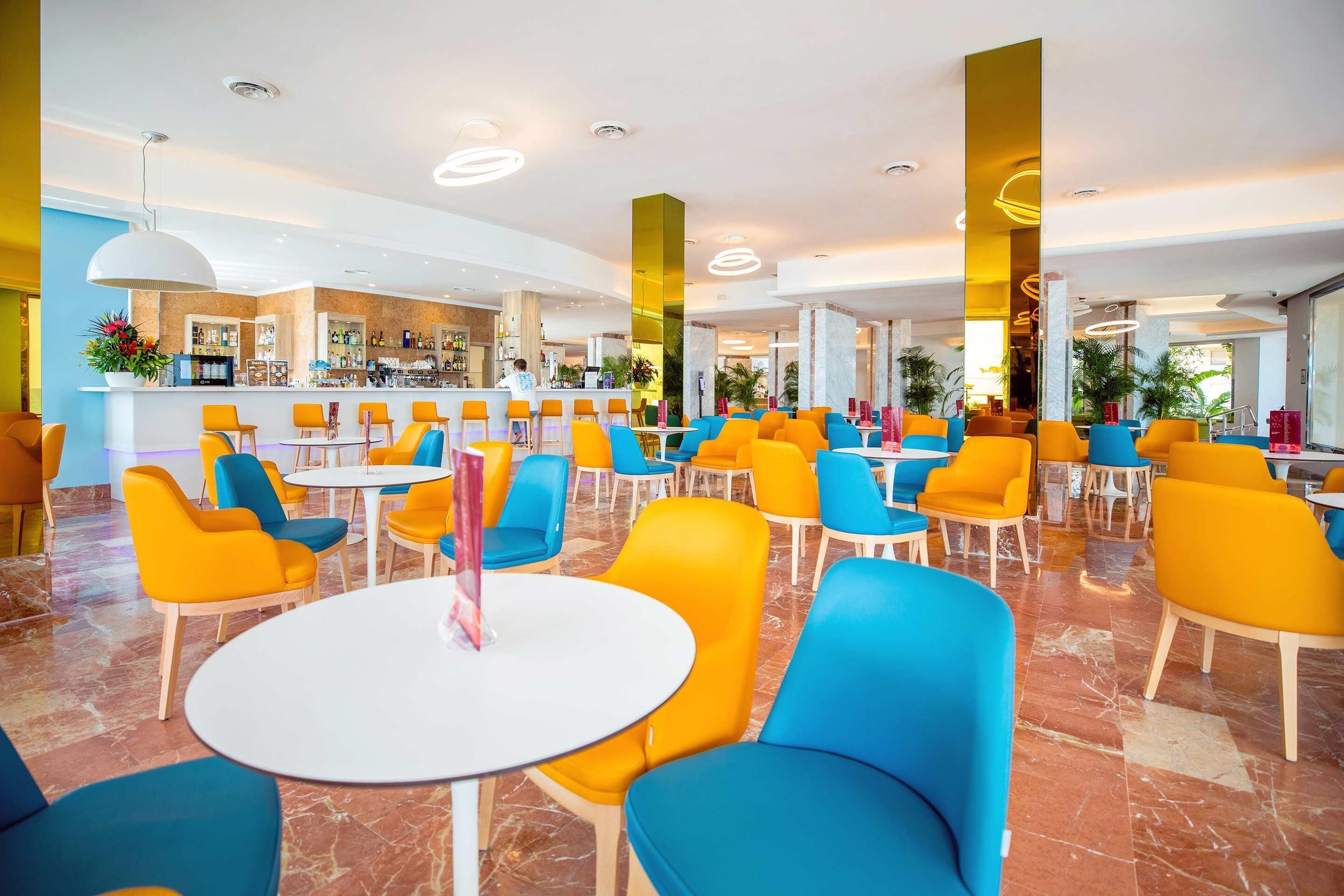Un hall d’hôtel spacieux, doté de plusieurs espaces de détente, d’un bar et d’un comptoir d’accueil.