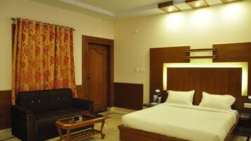 A hotel room with a bed, a sofa, a coffee table, and a door.