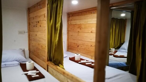 Una habitación tipo cabaña de madera con dos camas, cada una con cabecero de madera, un espejo y una mesita de noche con artículos de aseo.