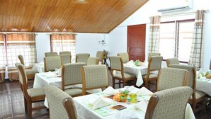 A dining area with wooden ceiling, multiple tables with chairs, and a view of the outside through windows. - Trust Lodge (Sekondi-Takoradi)