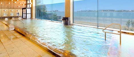 Una piscina interior con vista a un cuerpo de agua y un paisaje urbano.