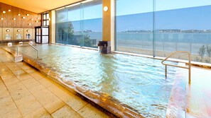 An indoor swimming pool with a view of a body of water and a cityscape. - Ooedo Onsen Monogatari Nagayama (Kaga)