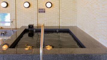 A hot spring bath area with tiled walls and a wooden floor.