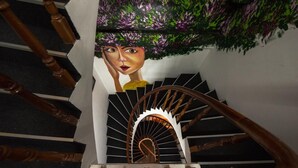 Una escalera de caracol con barandillas de madera y un mural en la pared.