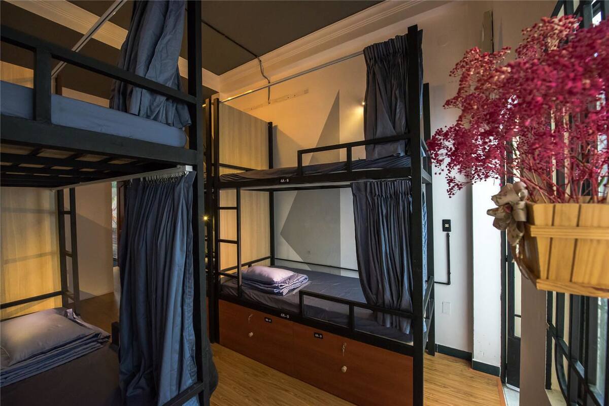 A bunk bed room with curtains, a wooden cabinet, and a vase with flowers.