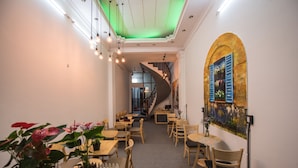 Un restaurante con mesas y sillas de madera, un techo iluminado en verde y una escalera que conduce a un nivel superior.