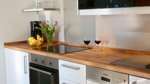 Een moderne keuken met een houten aanrecht, een ingebouwde oven, een vaatwasser en een wijnglas op het aanrecht.