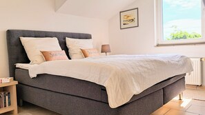 A bed with a grey headboard, white bedding, and two pillows with text.