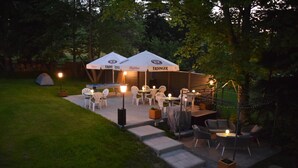 An outdoor patio area with tables and chairs, a tent, and umbrellas labeled "ERDINGER." - Pension Lachmann (Koenigstein)