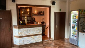 A bar area with a stone counter, wooden cabinets, and a beverage dispenser. - Pension Lachmann (Koenigstein)