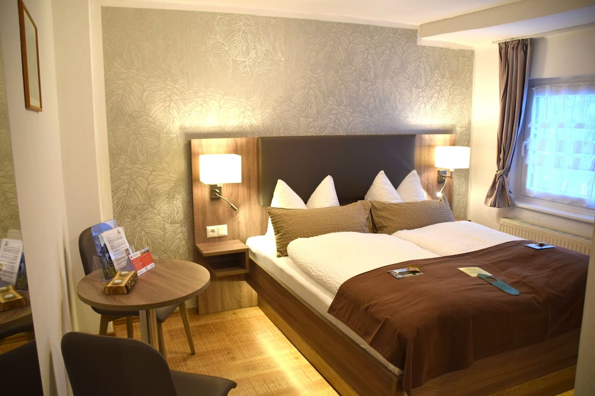 Una habitación de hotel con cama, mesitas de noche, escritorio y una silla.