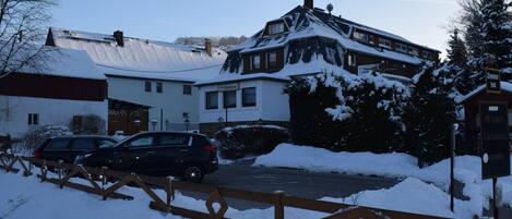 A residential area with snow-covered houses, a wooden gate, and a parked car.