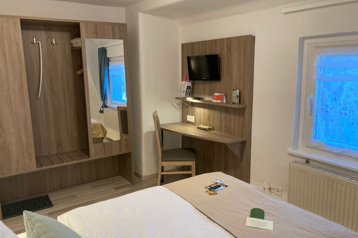 Habitación de hotel con cama, escritorio, silla, televisión y ventana con vistas.