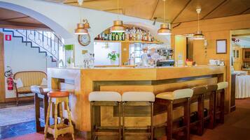 Un espace bar avec des tabourets en bois, un comptoir et des lampes suspendues.